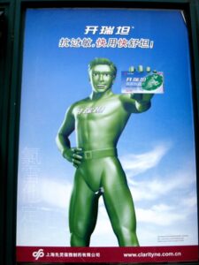 Green painted Chinese man holding a credit card.