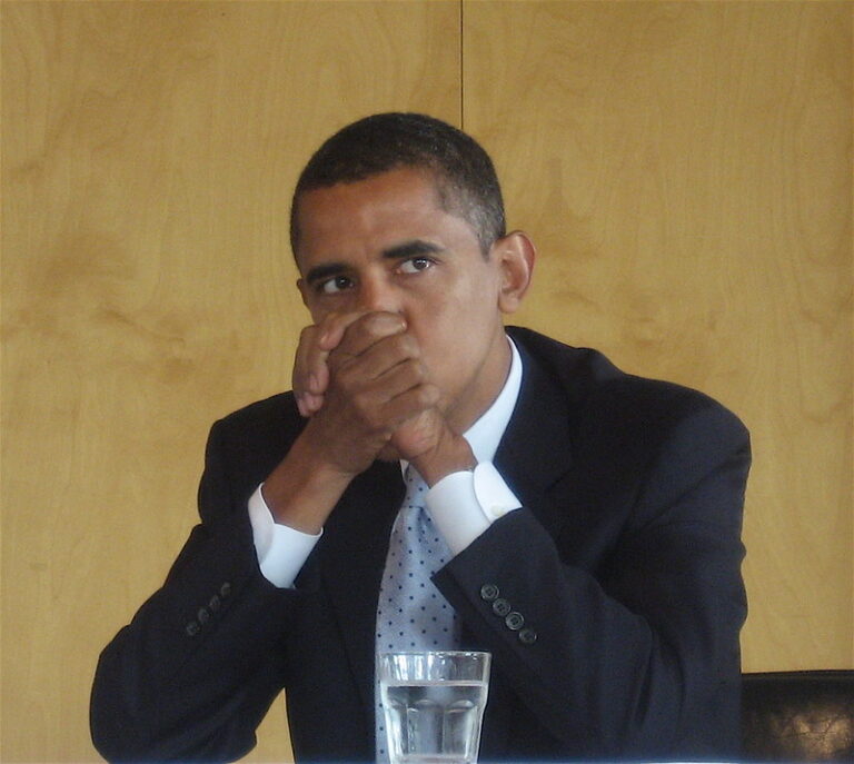 Obama with hands clasped in front of his face