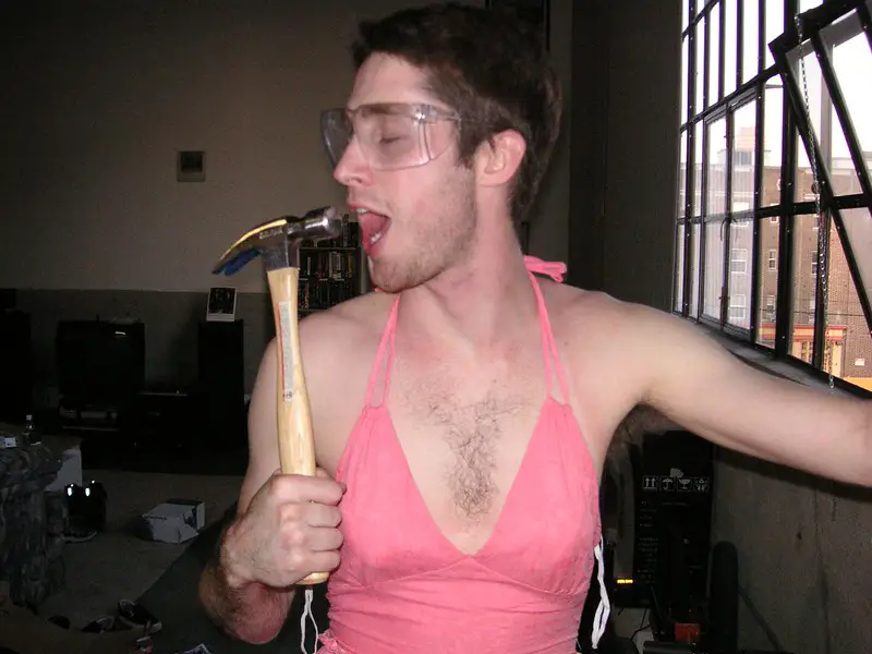 Man dressed in pink singing to hammer.